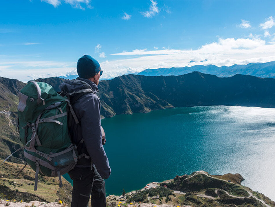Nachhaltiger Wandertourismus Ein Mann blickt von oben auf einen Bergsee
