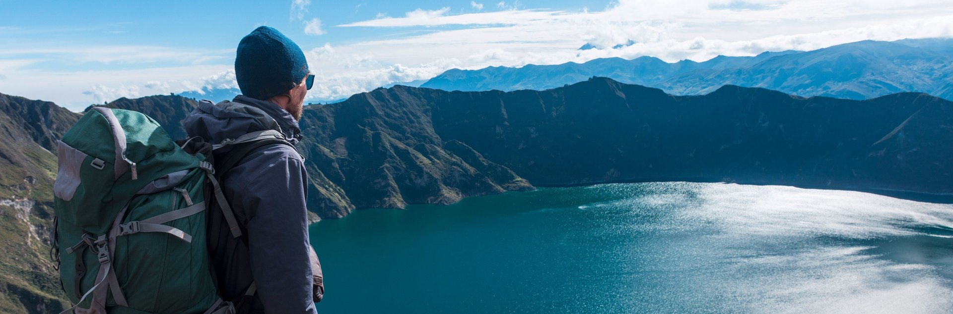 A man looks down on a mountain lake from above